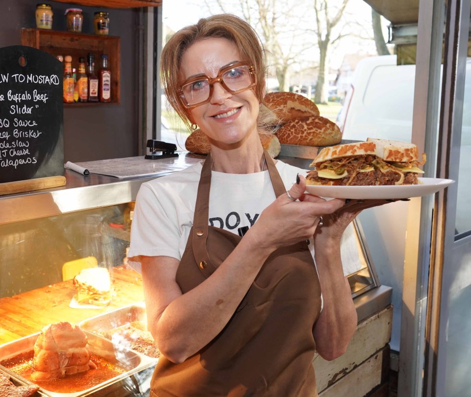 Woman holding a large sandwich in a sandwich shop.