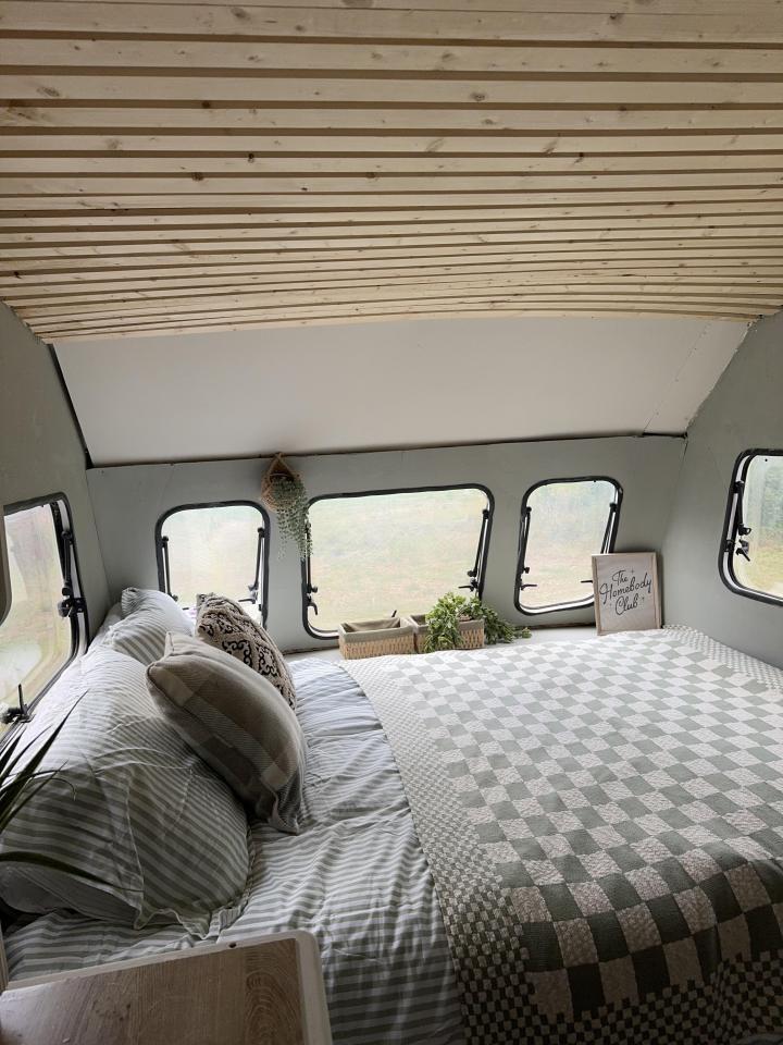 Renovated caravan interior with bed and wood paneling.