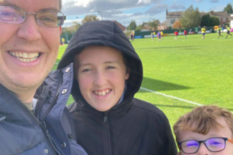 A man and his two sons at a soccer field.