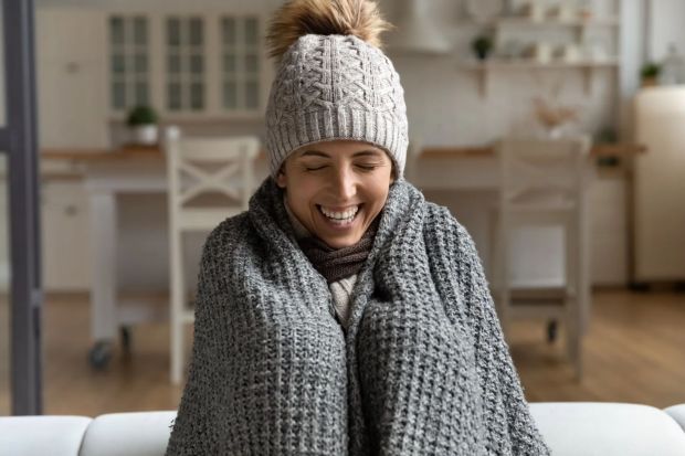 Woman wrapped in a blanket smiling.