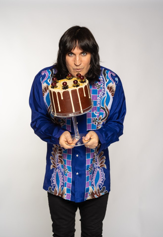 A man in a patterned shirt holds up a chocolate cake.