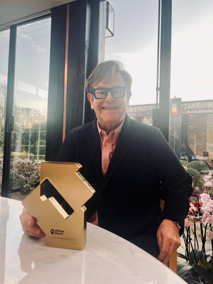 Sir Elton John holding his Official Number 1 Album Award for Diamonds.