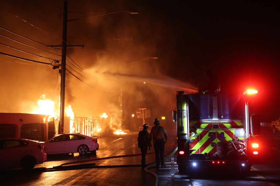 Firefighters battling a large fire at night.