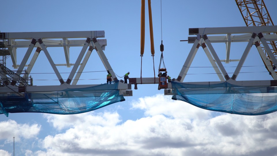 Workers connecting two 500-ton sections of a stadium's mega-truss.