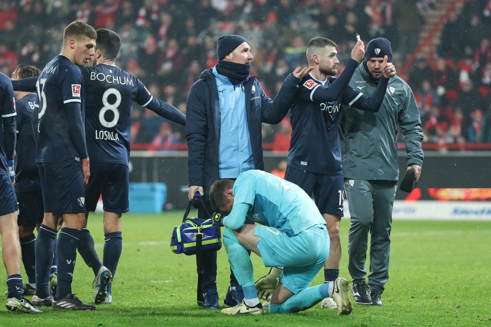 VfL Bochum goalkeeper Patrick Drewes is attended to after being hit by a lighter thrown from the crowd.