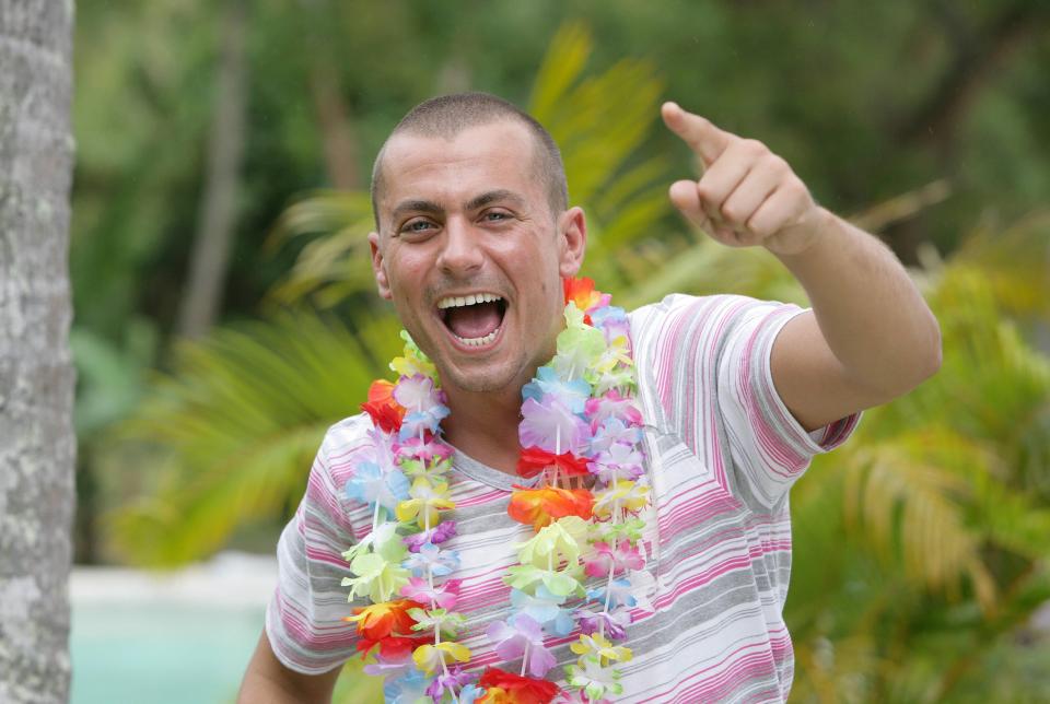 Man wearing a lei and pointing.