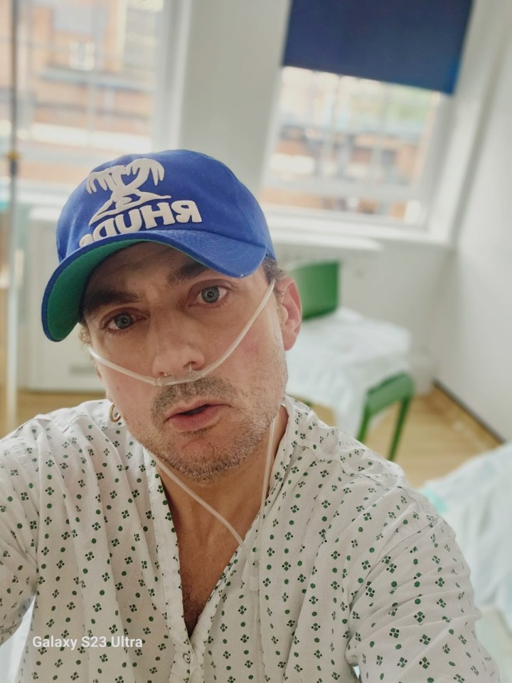 Man in hospital gown and baseball cap using oxygen.