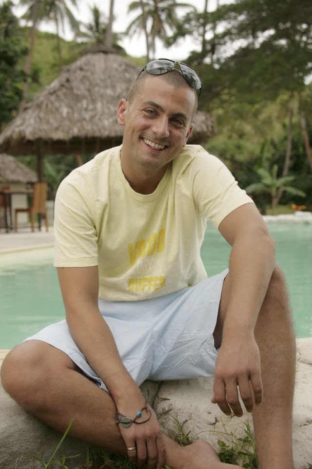 Paul Danan sitting by a pool in a tropical location.