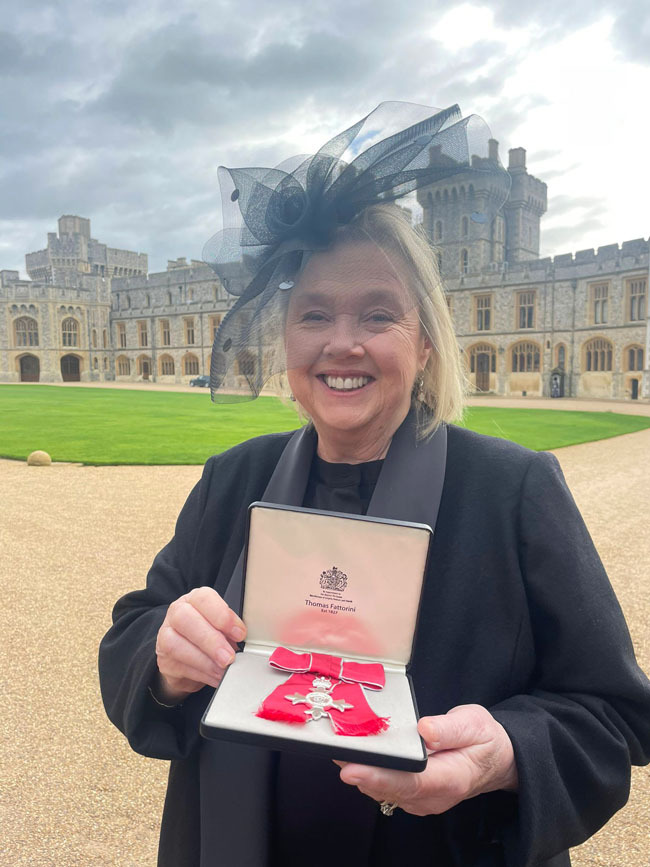 Pauline Quirke, MBE, holding her medal outside Windsor Castle.