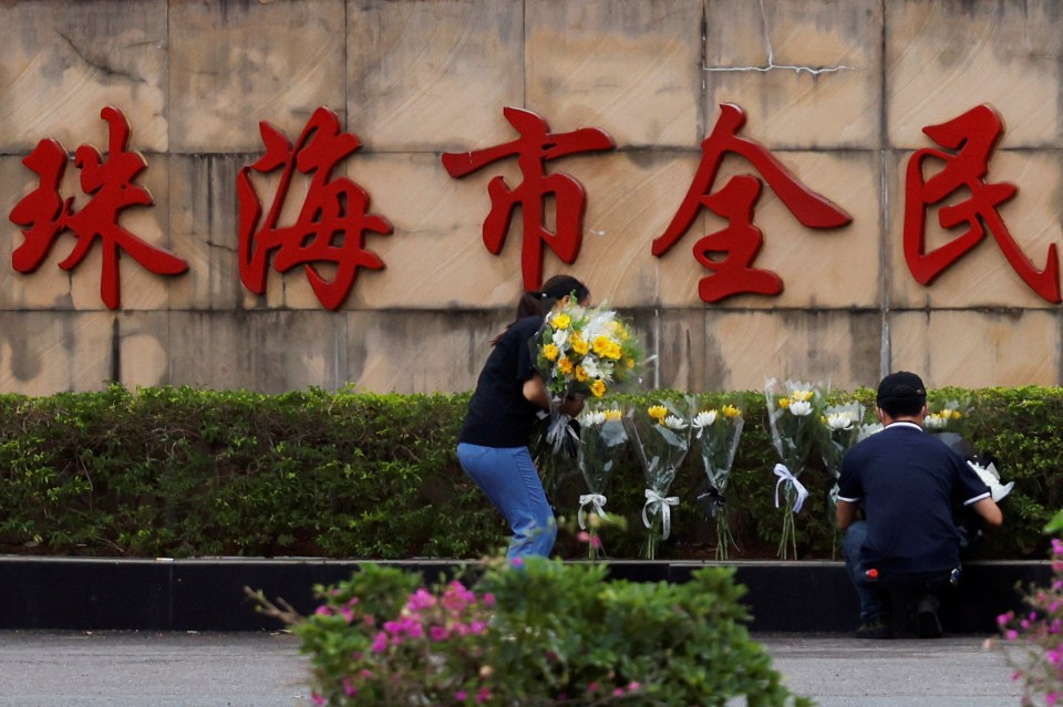 People placing flower bouquets at a memorial.