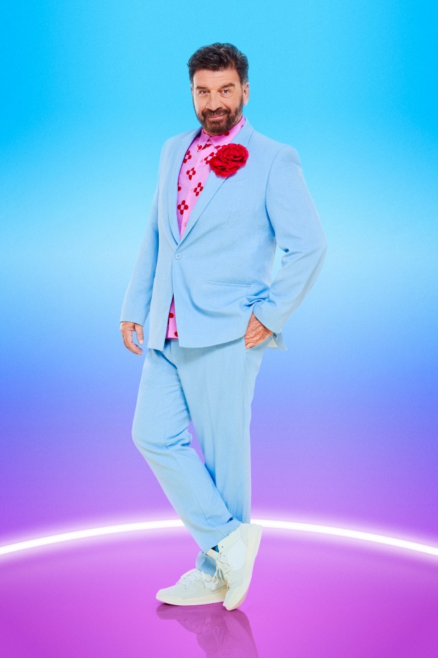 Nick Knowles in a light blue suit, pink shirt, and white trainers.