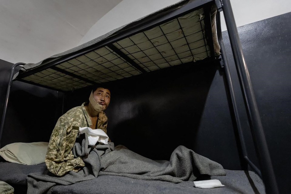 A wounded North Korean soldier sits on a bunk bed in Ukrainian custody.