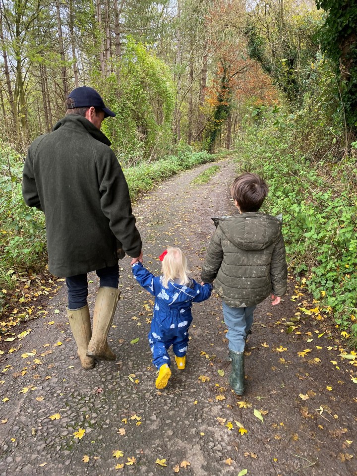 A man and two children walking down a path in a wooded area.