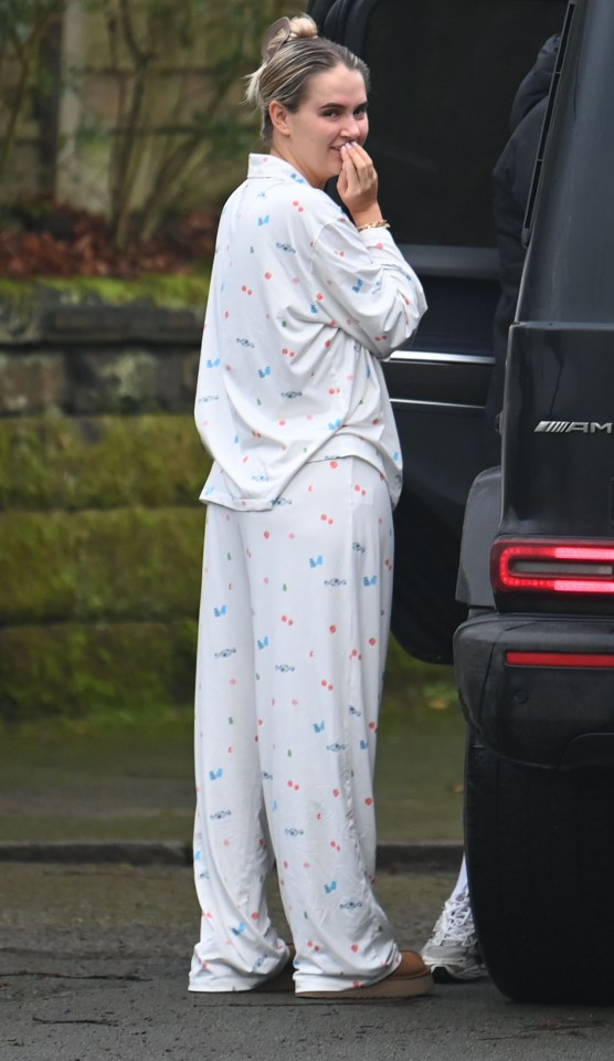 Woman in pajamas smiling near a car.