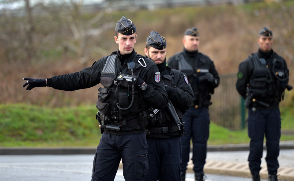 Police officers block a road near an industrial area where the suspects in the shooting attack at the satirical French magazine Charlie Hebdo headquarters were