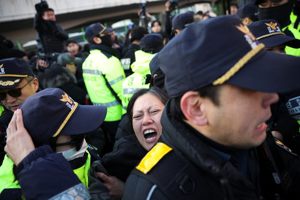 Police officers drag away a pro-Yoon protester