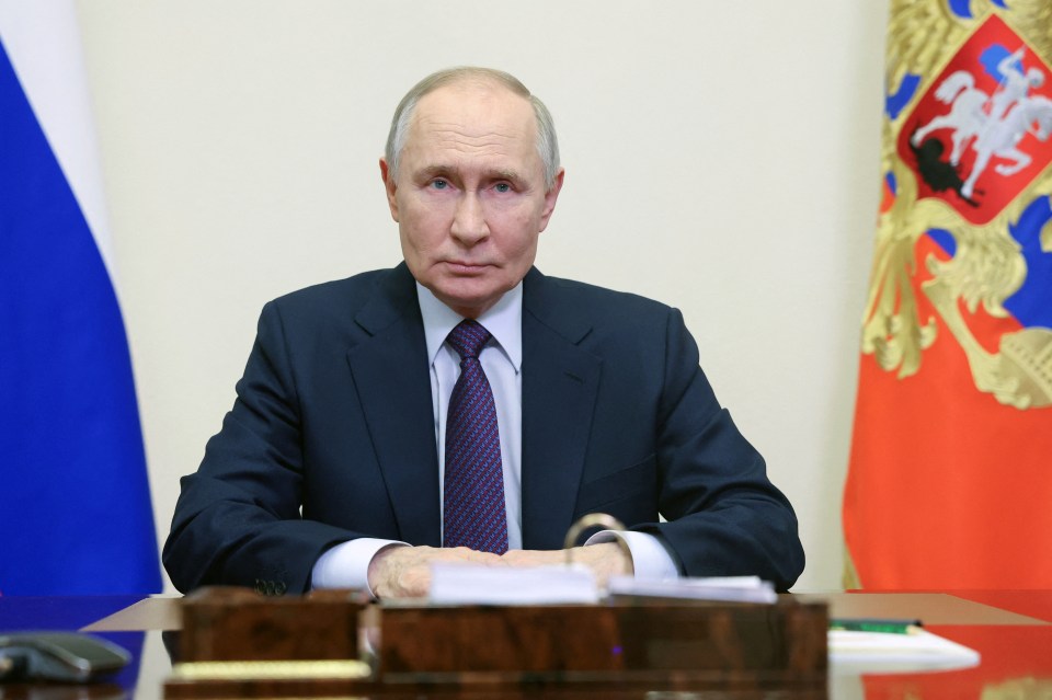 Vladimir Putin sitting at a desk.