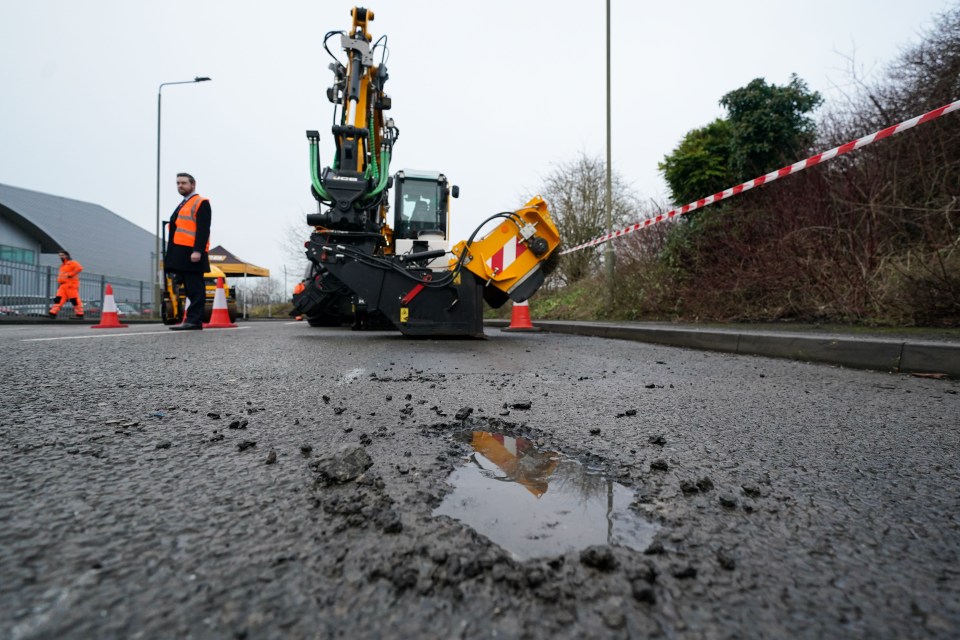 Pothole repair machine next to a pothole.