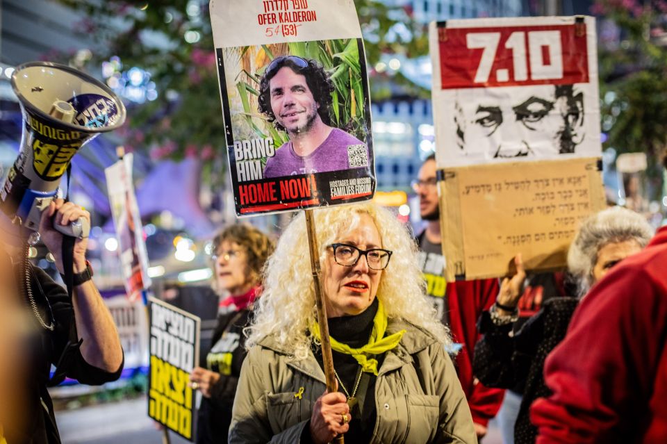 Protestor holding a sign with a photo of Ofer Calderon and the words "Bring Him Home Now".