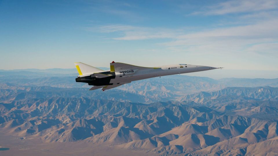 Supersonic aircraft XB-1 flying over mountains.