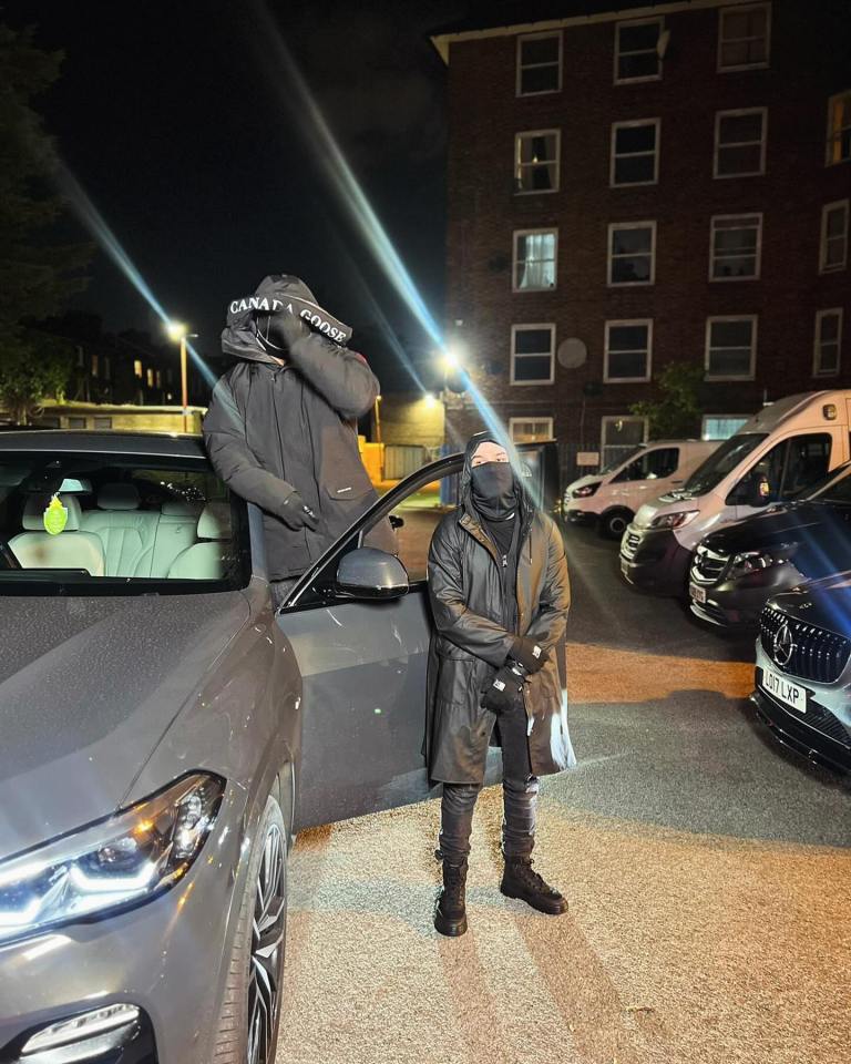 Two people in dark clothing standing by a car at night.