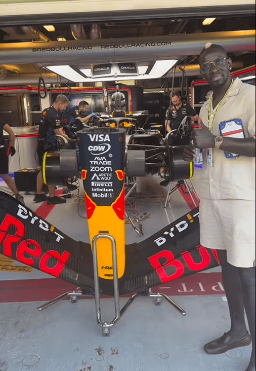 Man giving thumbs up next to a Red Bull Formula 1 car.