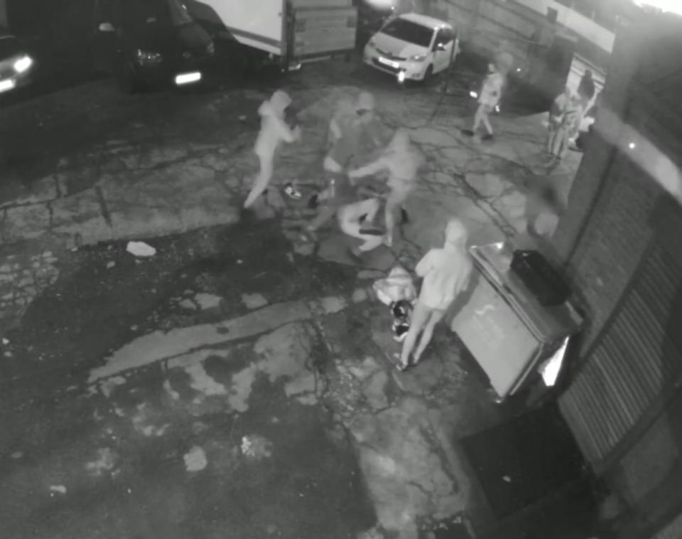 Security camera footage of a group of people assaulting another person.