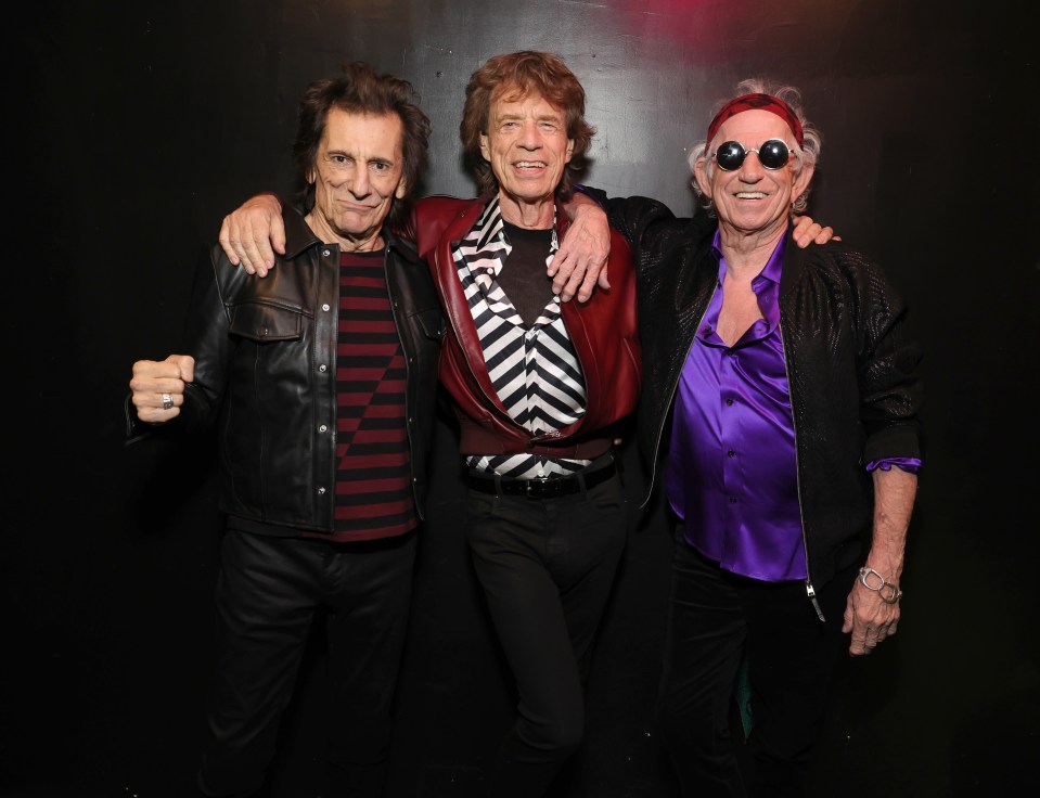 Ronnie Wood, Mick Jagger, and Keith Richards backstage at a Rolling Stones event.