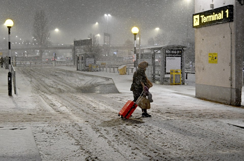 A traveller braves the wintry conditions arriving at Manchester Airport