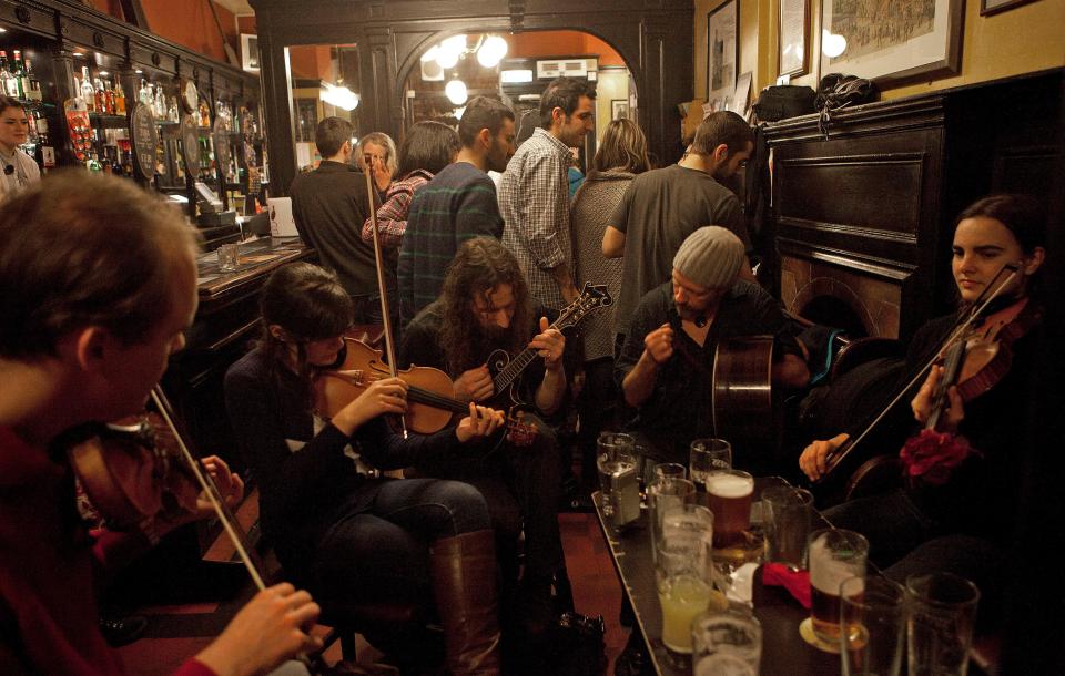 Musicians playing violins and mandolin in a pub.