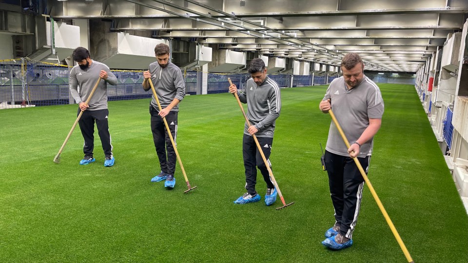 Four men raking a soccer field at the Santiago Bernabéu Stadium.