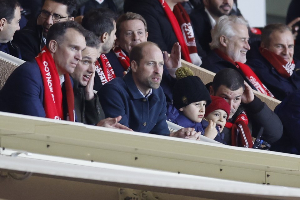 Prince William watching a soccer match with his children and other spectators.