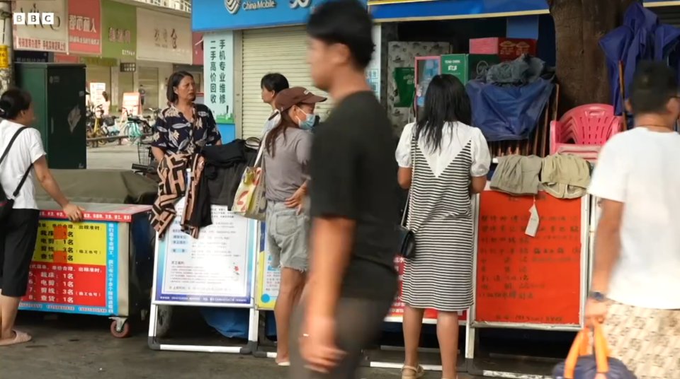 People shopping at an outdoor market stall.