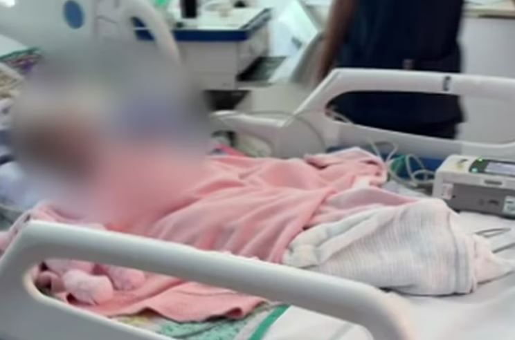 Blurred image of a baby in a hospital bed.