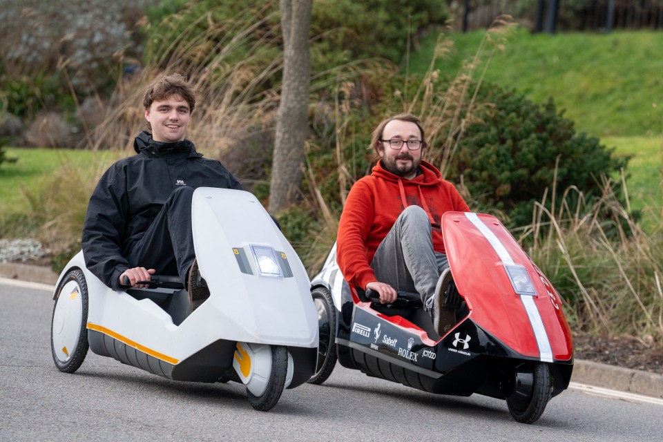 Two people driving Sinclair C5 electric vehicles.