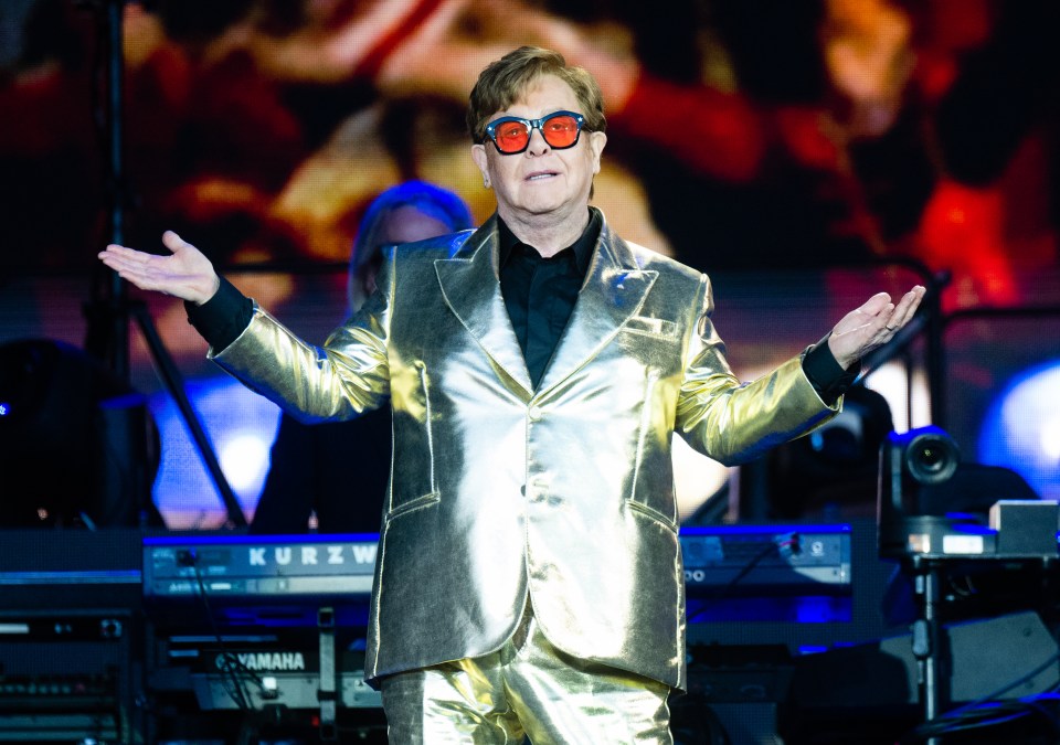 Elton John performing on stage in a gold suit.