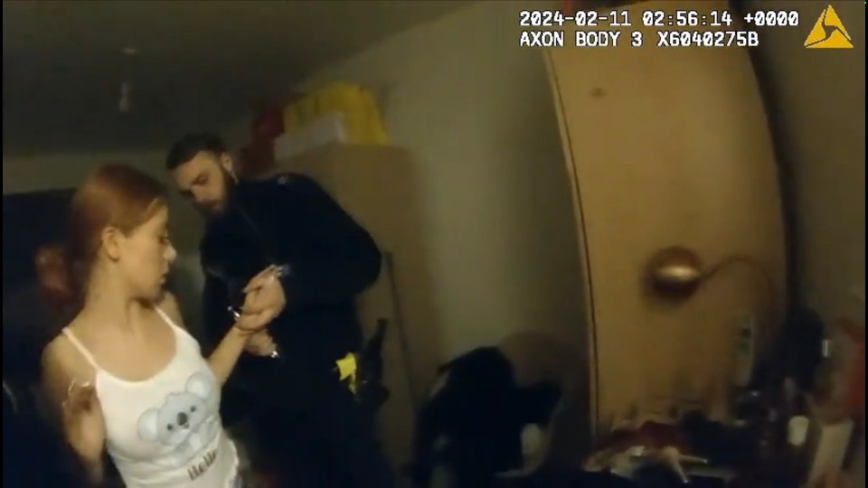 CCTV footage of a young woman being handcuffed by a police officer.