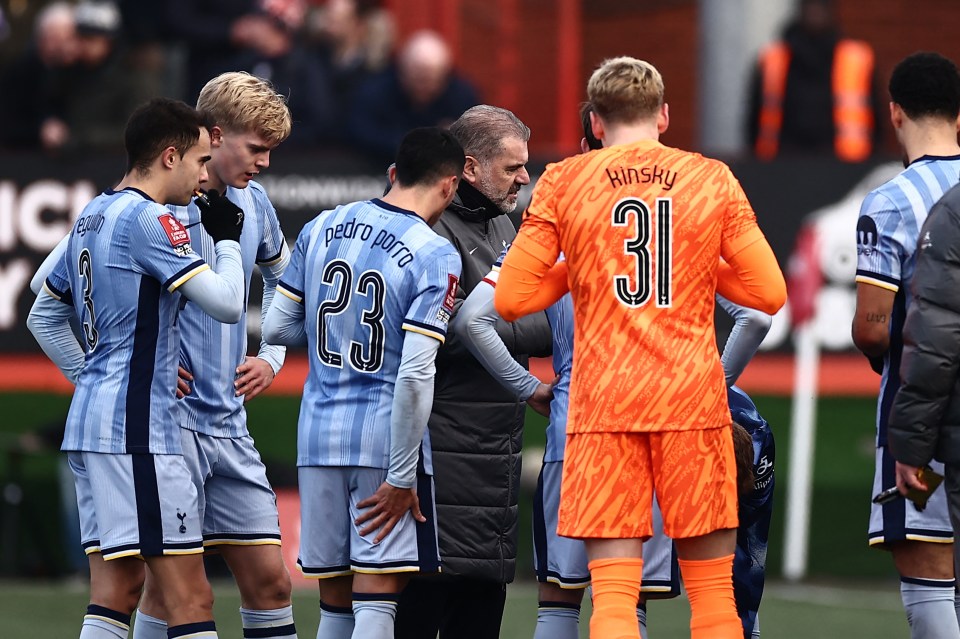 Tottenham Hotspur's coach speaking with players during a match.