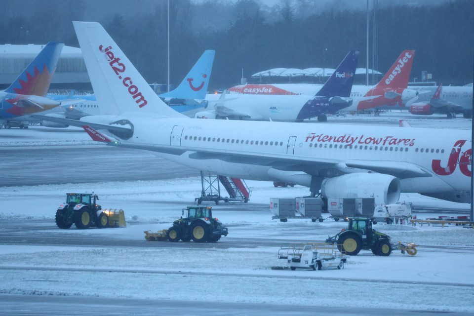 Tractors clearing snow from around airplanes at a snow-covered airport.