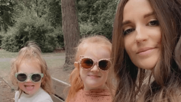 Photo of a woman and two young girls wearing sunglasses outdoors.