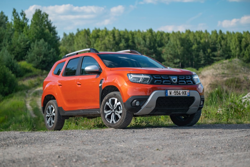 Orange Dacia Duster parked on a gravel road.