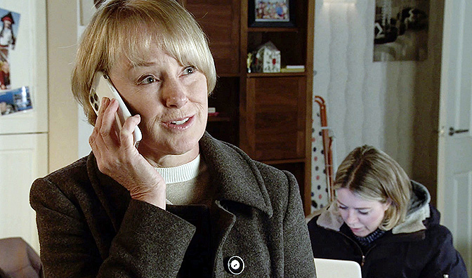 A woman on a phone call, another woman is visible in the background.