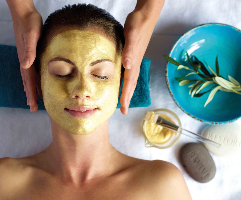 Woman receiving a gold facial treatment.