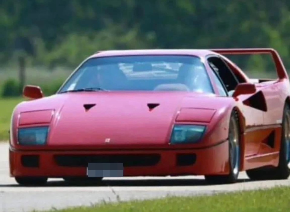 Red Ferrari F40 driving on a road.