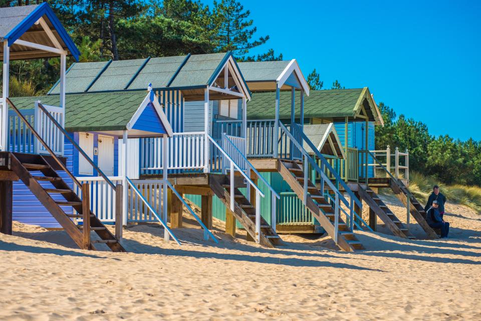 Colorful beach huts on a sandy beach.