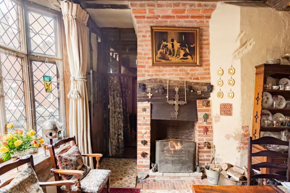 Cozy room with fireplace, antique furniture, and stained-glass window.