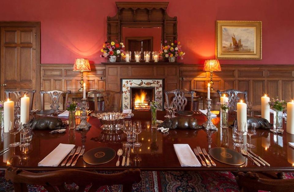 Formal dining room in Lostwithiel Manor with a fireplace and a long table set for a meal.