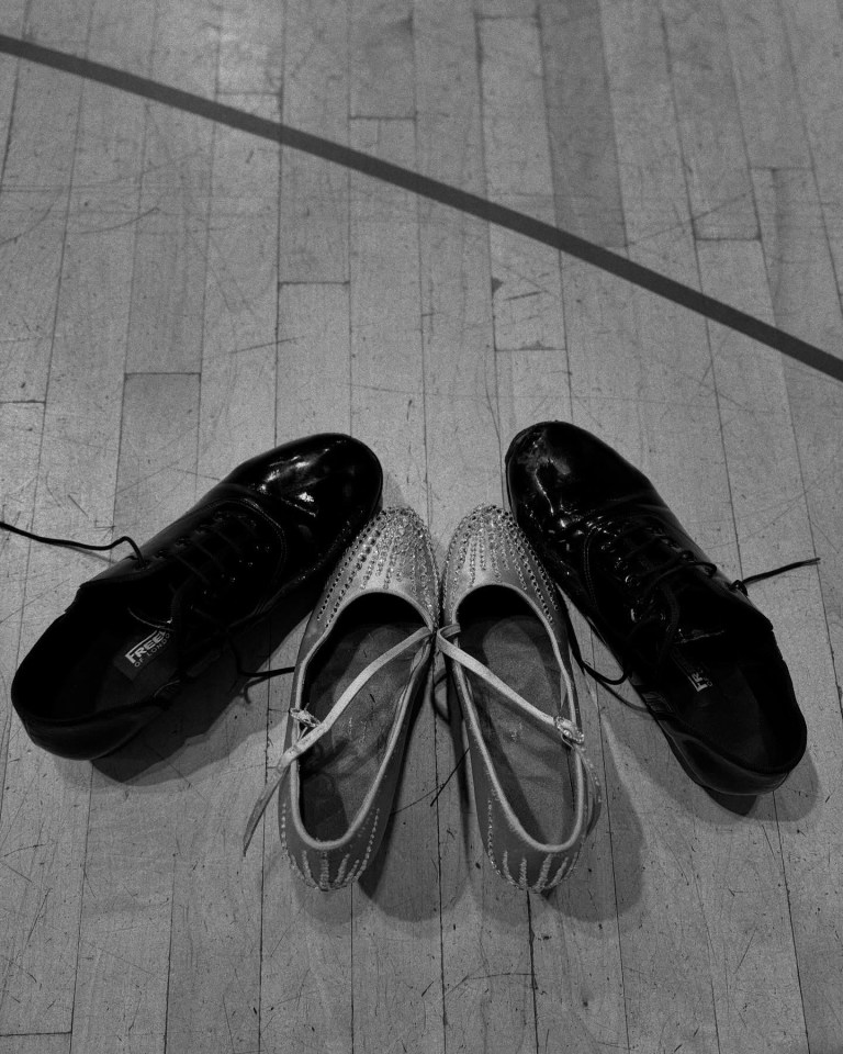 Two pairs of shoes on a wood floor.