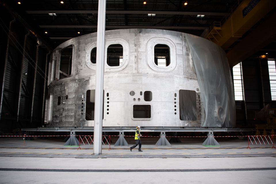 Technician walking past the cryostat of the ITER nuclear fusion machine.