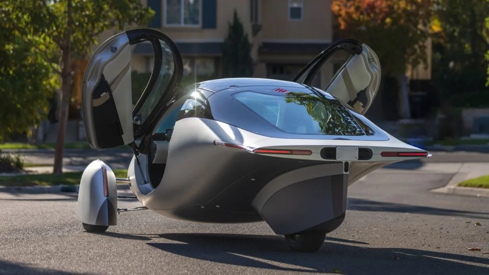 Three-wheeled solar-powered car with doors open.